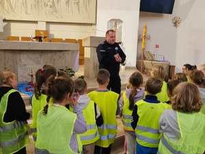 asp. Dawid Mucha przekazujący dzieciom w kościele wiedzę  dotyczącą bezpieczeństwa na drogach